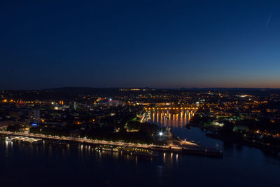 Illuminated cityscape against clear blue sky at night