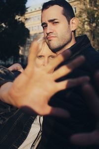 Portrait of couple showing stop gesture against trees