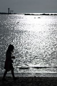 Side view of boy standing in sea against sky