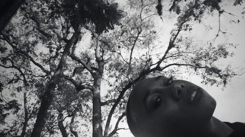 Low angle view of young woman against trees