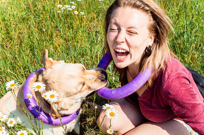 A girl playing with a labrador retriever dog on the summer field with chamomilles