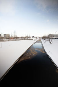 Frozen canal against sky during winter