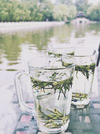 Drink glasses on table against lake
