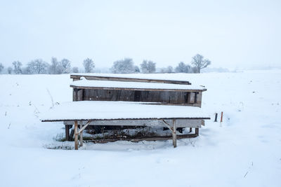 Built structure on snow covered field against clear sky