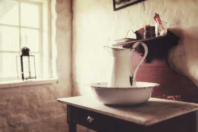 Close-up of old water jug on table at home