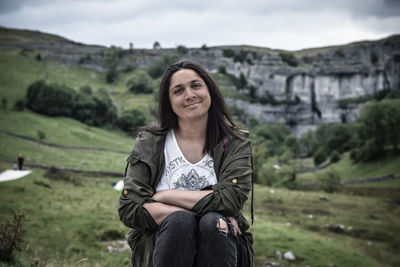 Portrait of young woman sitting against landscape