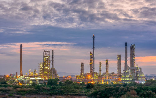 Illuminated factory against sky during sunset