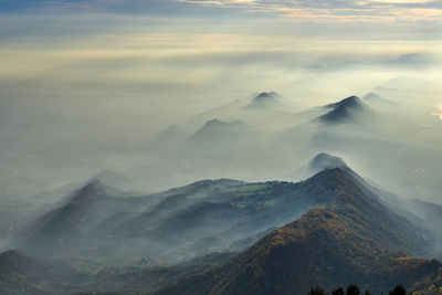 Scenic view of mountains with mist against sky 