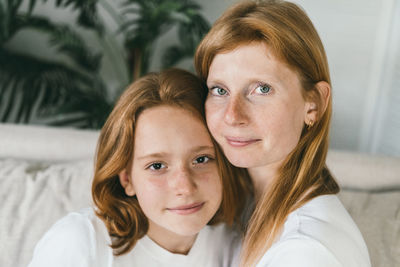 Mom and daughter with red hair. mom and daughter teen hugging at home on the couch.