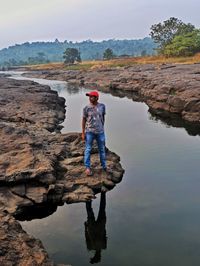 Full length of man standing on rock against sky