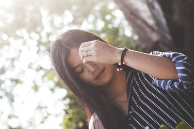 Young woman standing against trees