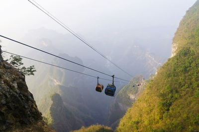 Overhead cable car over mountains against sky