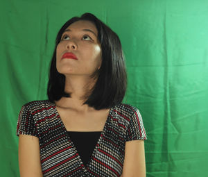 Portrait of young woman looking away against wall