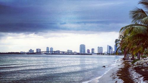 Sea by cityscape against sky