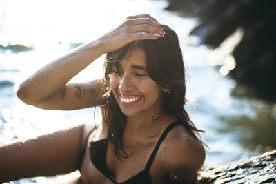 Young latina woman laughing by the ocean at golden hour in summertime