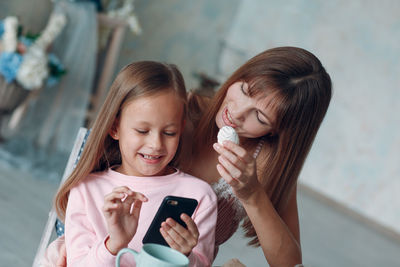 Mother and girl using smart phone at home