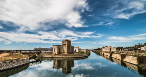 Historic building by river against cloudy sky