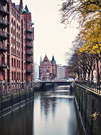 Canal by buildings against sky in city