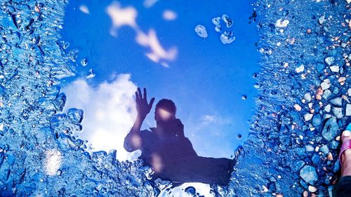 Close-up of hand against blue sky