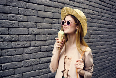 Young woman eating food against wall