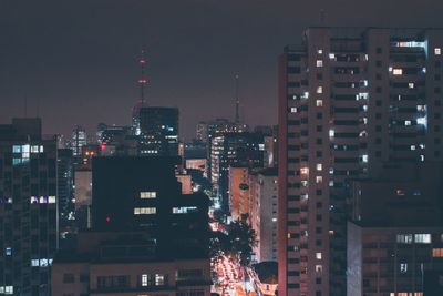 Illuminated buildings in city against sky at night