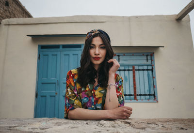 Portrait of young woman against house in building