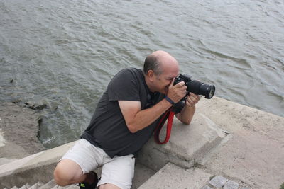 High angle view of man photographing from stairway by sea