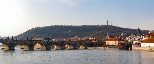 Bridge over river in city against clear sky