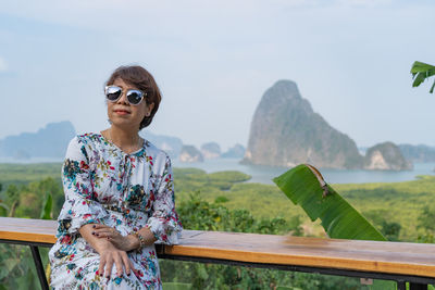 Mature woman wearing sunglasses while sitting against landscape