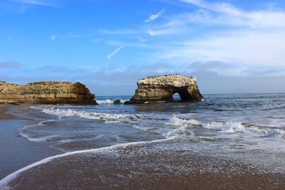 Rock formation on beach against sky