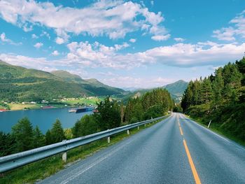Road by trees against sky
