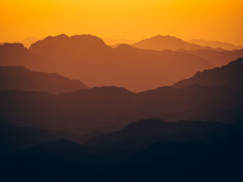 Scenic view of silhouette mountains against romantic sky at sunset