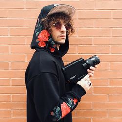 Man wearing sunglasses standing against brick wall