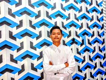 Portrait of smiling young man standing against wall