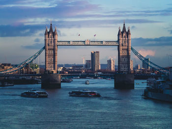 View of suspension bridge over river against cloudy sky