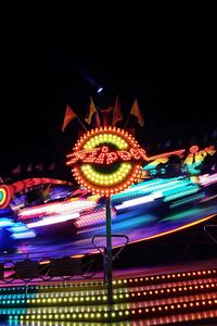 Low angle view of illuminated ferris wheel against sky at night