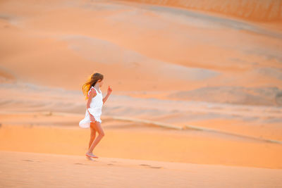 Full length of woman standing on sand dune