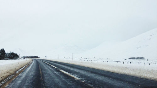 Empty road passing through snow covered mountain