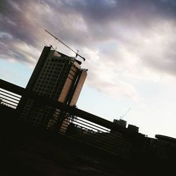 Low angle view of crane against cloudy sky