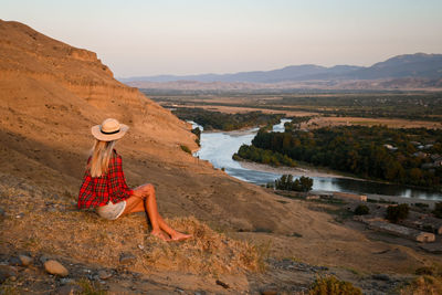 A girl sitting on the rock at sunset, arid landscape 