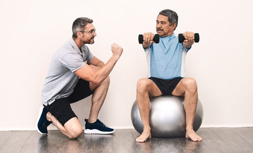 Coach assisting man while exercising in gym