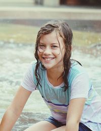 Portrait of smiling young woman enjoying in rain