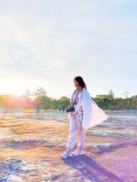 Rear view of woman standing on field against sky