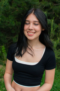 Portrait of young woman standing against trees