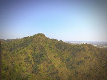 Scenic view of landscape and sea against clear sky