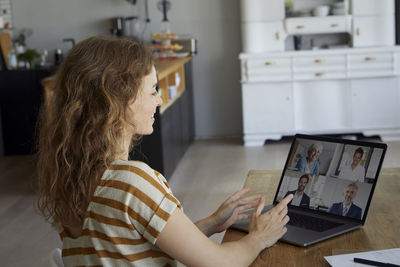 Woman talking on video conference through laptop while sitting at home