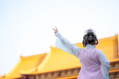 Rear view of woman with umbrella against clear sky