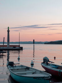 Boats moored on sea against sky during sunset