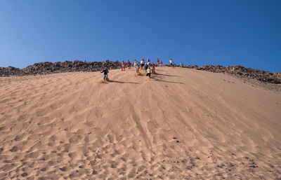 People on desert against clear sky