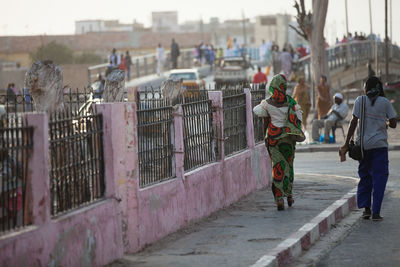 Rear view of people walking on sidewalk